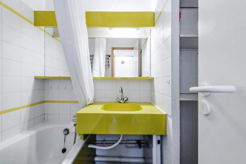 La salle de bains est pourvue d'un lavabo jaune et d'une baignoire. dans l'établissement Résidence Le Sextant - maeva Home - Studio 4 Personnes Sélection MAE-6066, à La Plagne Tarentaise