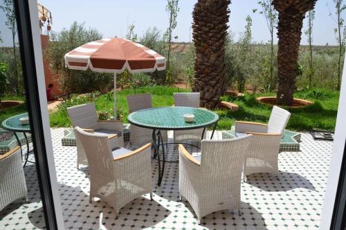 a patio with a table and chairs and an umbrella at Villa Palmengarten Meknès bei Fes in Meknès