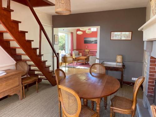 une salle à manger avec une table, des chaises et un escalier dans l'établissement Maison de charme vue sur mer pour 6 pers, à Quinéville