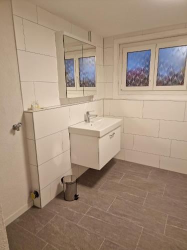 a white bathroom with a sink and two windows at Haus Christania, Obergeschoss, Unterbäch Wallis in Unterbäch