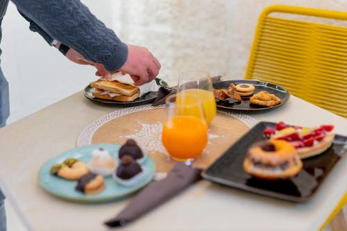 a table topped with plates of food and orange juice at Vico Bianco Raro Smart Rooms Collection in Ostuni