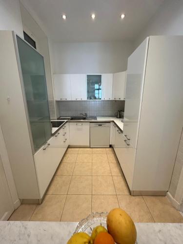 - une cuisine avec des placards blancs et un bol de fruits dans l'établissement Ancien Palace 4couchages Vue Mer, à Menton
