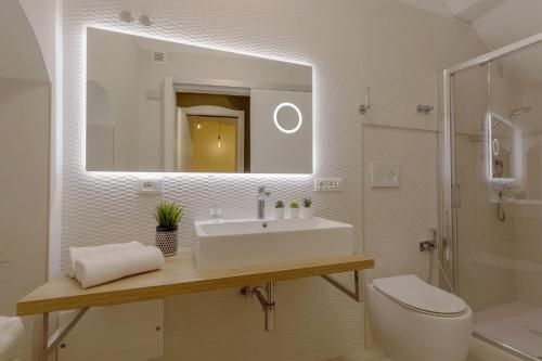a bathroom with a sink and a toilet and a mirror at Martini Castello Boutique Rooms - Historic Center & Cathedral in Cagliari
