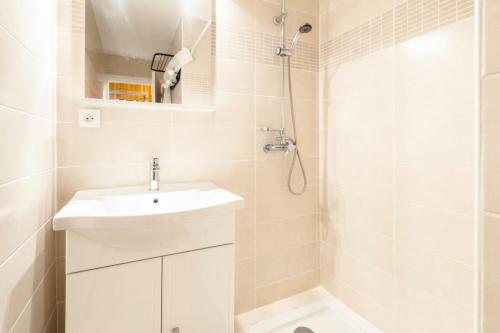y baño blanco con lavabo y ducha. en Appartement 6 pers. à 30m des remontées - Maeva Particuliers - 3 Pièces 6 Personnes Sélection 138716 en L'Alpe-d'Huez