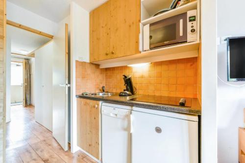 une cuisine avec un évier et un micro-ondes dans l'établissement Résidence Les Constellations - maeva Home - 2 Pièces 5 Personnes Sélection MAE-8856, à La Plagne Tarentaise