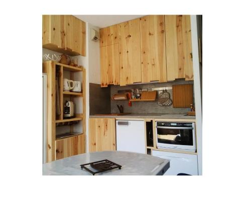 une cuisine avec des armoires en bois et un comptoir dans l'établissement Appartement au pied des pistes à Auris en Oisans - Appartement 2 pièces 6 personnes - Confort MAE-9077, à Auris