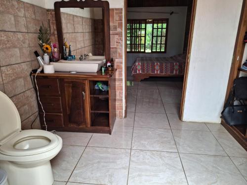 a bathroom with a toilet and a sink and a mirror at VILLA ESMERALDA in Siquirres