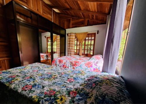 um quarto com uma cama com colcha floral em VILLA ESMERALDA em Siquirres
