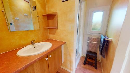 une salle de bain avec un lavabo, un miroir et une fenêtre dans l'établissement Mobil Home 40 Grand Confort, à Brem-sur-Mer
