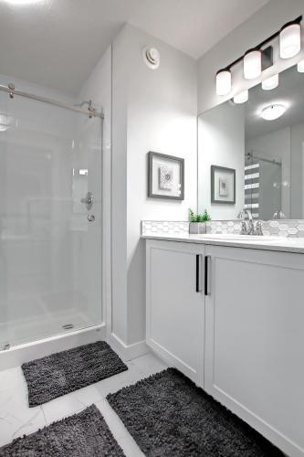 a white bathroom with a shower and a sink at Beautiful 3Bed-with AC-Close to Spruce Meadows & Mountains in Calgary