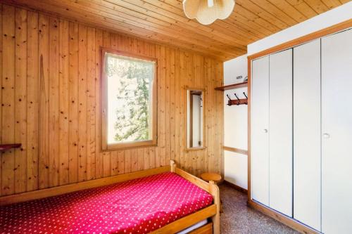 ein Schlafzimmer mit einem roten Bett in einem Holzzimmer in der Unterkunft Chalet le Séchet - Maeva Particuliers - 2 Pièces 4 personnes Confort 140619 in Bellentre