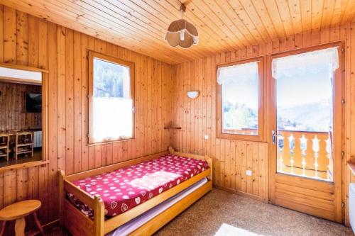 Zimmer mit einem Bett in einem Holzzimmer mit Fenstern in der Unterkunft Chalet le Séchet - Maeva Particuliers - 2 Pièces 4 personnes Confort 140622 in Bellentre