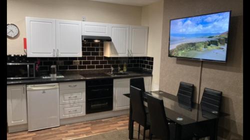 a kitchen with a table and a tv on the wall at Phillips Apartments in Blackpool