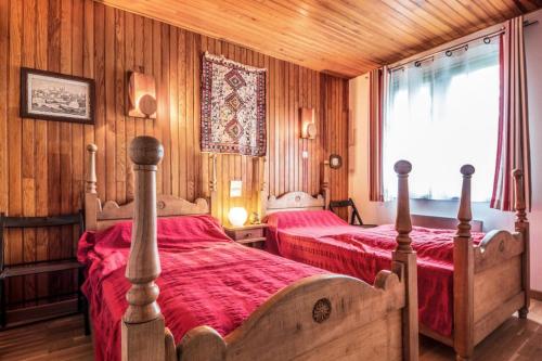 - 2 lits dans une chambre dotée de murs en bois et d'une fenêtre dans l'établissement Appartement 6 pers. belle vue montagne - maeva Home - Appartement 3 Pièces 6 Personnes - Sélection MAE-0673, à Font-Romeu-Odeillo-Via