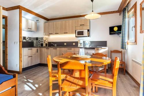 une cuisine et une salle à manger avec une table et des chaises en bois dans l'établissement Quartier La Forêt - maeva Home - 3 Pièces 6 Personnes Sélection MAE-3341, à Valmorel