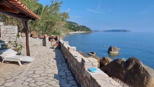 a stone retaining wall with a chair and the ocean at Refugium direkt am Meer in Marina di Pisciotta in Pisciotta