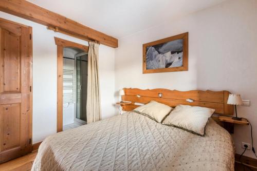 ein Schlafzimmer mit einem Bett mit einem hölzernen Kopfteil in der Unterkunft Résidence Les Fermes du Soleil - maeva Home - 3 Pièces 6 Personnes Sélection MAE-4102 in Les Carroz d'Araches
