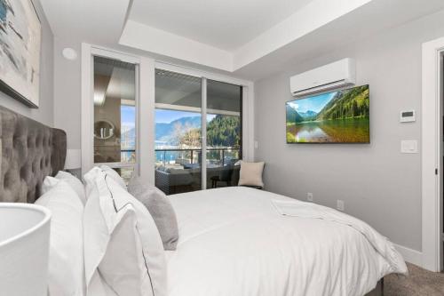 a bedroom with a white bed and a large window at Lakeside Escape at the Oasis in Harrison Hot Springs