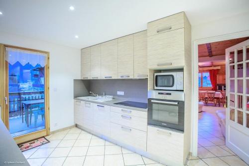 une cuisine avec des armoires blanches et un micro-ondes dans l'établissement Chalet à La Chapelle d'Abondance proche pistes - 10 Pièces 20 personnes MAE-8779, à La Chapelle-dʼAbondance