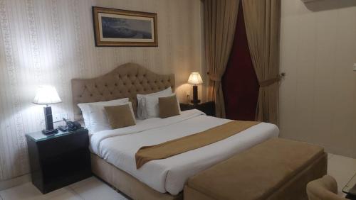 - une chambre avec un grand lit dans une chambre d'hôtel dans l'établissement Javson Airport Hotel, à Sialkot