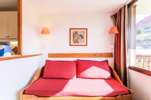 - un lit avec 2 oreillers rouges dans l'établissement Résidence Les Mélèzes - maeva Home - Appartement 2 Pièces 6 Personnes Selection MAE-1345, à Huez