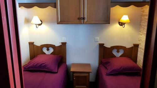 - 2 lits dans une petite chambre avec des oreillers violets dans l'établissement Résidence Les Terrasses d'Azur - maeva Home - 2 Pièces 4 Personnes Confort MAE-1522, à Isola 2000