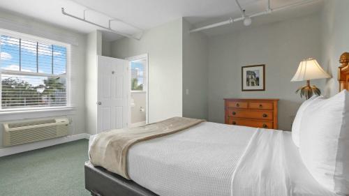 a white bedroom with a bed and a window at Crystal Bay Historic Hotel in St Petersburg