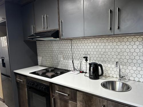 a kitchen with a sink and a stove and cabinets at Katlego in Bloemfontein