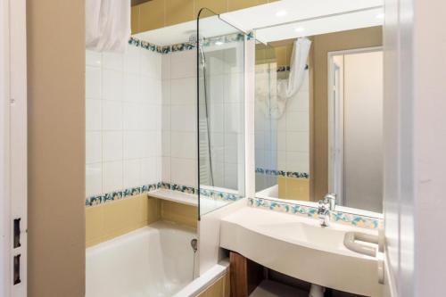 ein Badezimmer mit einem Waschbecken, einer Badewanne und einem Spiegel in der Unterkunft Résidence Sépia - maeva Home - Appartement 3 pièces 7 pers Prestige 89 in Morzine