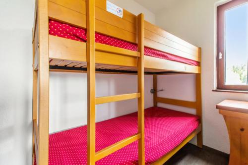 Cette chambre dispose de lits superposés avec 2 lits superposés et des draps rouges. dans l'établissement Résidence Les Mélèzes - maeva Home - 2 pièces 6 pers Confort MAE-3394, à Huez