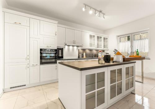 a kitchen with white cabinets and a large island at LoC-Luxus Apartment nahe Oldenburg in Wardenburg