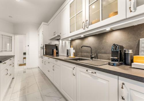 a kitchen with white cabinets and a sink at LoC-Luxus Apartment nahe Oldenburg in Wardenburg