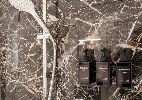 Baño con 2 botellas de jabón en una pared de mármol en LoC-Luxus Apartment nahe Oldenburg, en Wardenburg