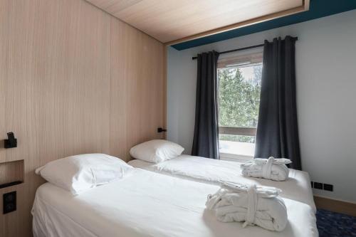 deux lits dans une chambre avec une fenêtre dans l'établissement Résidence Les Arcs 1950 Le Village - maeva Home - Appartement 2 pièces 4 personnes Prestige MAE-6302, à Bourg-Saint-Maurice