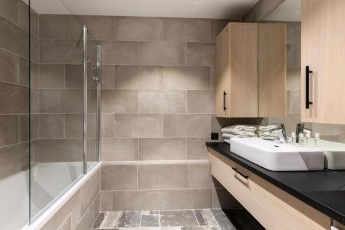 une salle de bain avec un lavabo, une douche et une baignoire dans l'établissement Résidence Les Arcs 1950 Le Village - maeva Home - Appartement 2 pièces 4 personnes Prestige MAE-6302, à Bourg-Saint-Maurice