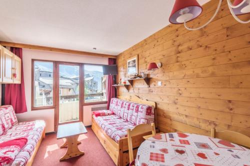 Cette chambre dispose de deux canapés et d'un mur en bois. dans l'établissement Résidence Le Douchka - maeva Home - Appartement 2 pièces 5 personnes Confort MAE-6972, à Morzine