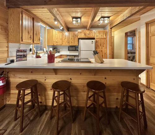 a kitchen with wooden cabinets and a large counter with stools at Chipmunk Lodge by NW Comfy Cabins in Leavenworth