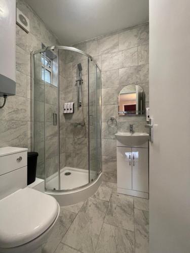 a bathroom with a shower and a toilet and a sink at Chamberlayne Inn in London