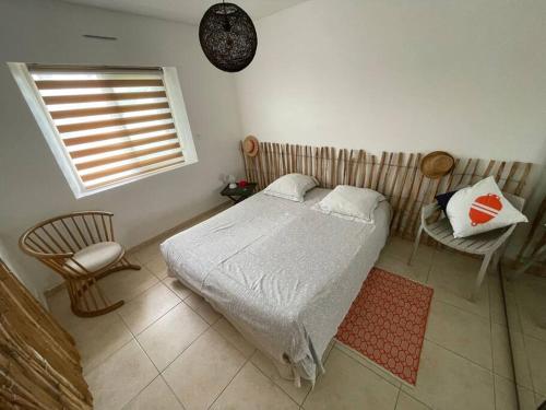 une chambre avec un lit, une chaise et une fenêtre dans l'établissement Maison familiale Cosy plage à pied, à Arzon