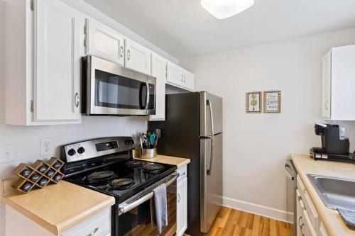 a kitchen with a stove and a stainless steel refrigerator at Mountainside Condo King Bed, Two Hot Tubs, Fireplace, Pool , on the Free Bus Route in Steamboat Springs