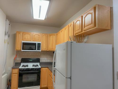 a kitchen with wooden cabinets and a white refrigerator at 2 Bedroom Bliss in College Point in College Point