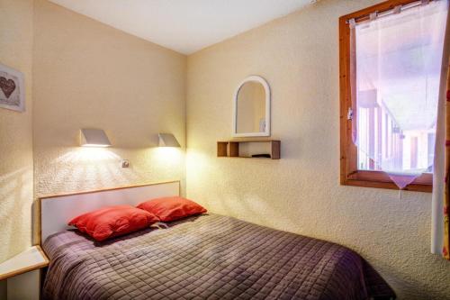 une chambre avec un lit avec des oreillers rouges et une fenêtre dans l'établissement Résidence Le Hameau du Sauget - maeva Home - 2 Pièces 4 Personnes Confort MAE-9861, à La Plagne Tarentaise
