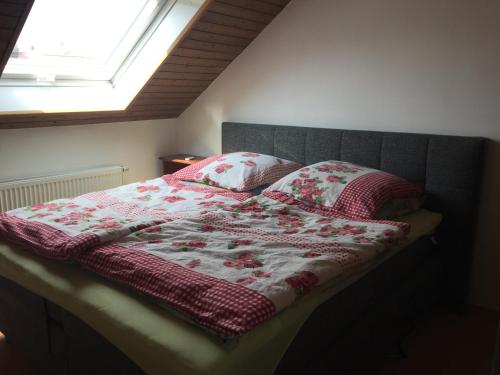 ein Bett mit einer roten und weißen Decke und Kissen in der Unterkunft Fewo Linda 2 in Gunzenhausen