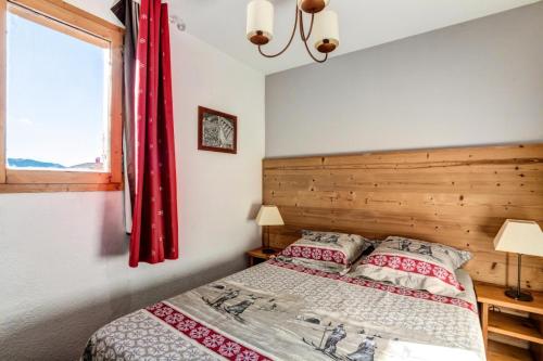une chambre avec un lit avec des rideaux rouges et une fenêtre dans l'établissement Résidence Les Constellations - maeva Home - 2 pièces 7 personnes Selection MAE-0489, à La Plagne Tarentaise