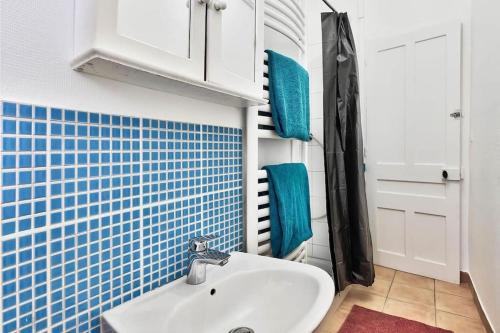 een badkamer met een wastafel en een blauwe tegelmuur bij Paisible T2 pour prof/famille in Saint-Fons