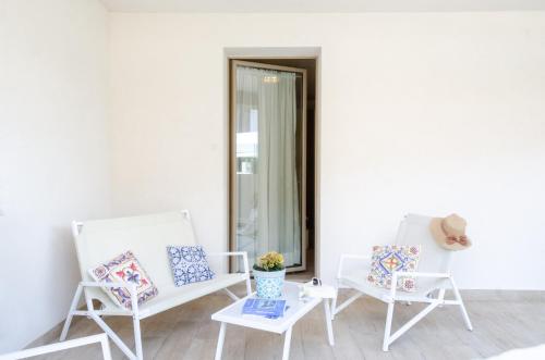 two white chairs and a table and a mirror at Mediterraneo Apartments ORO in Marzamemi