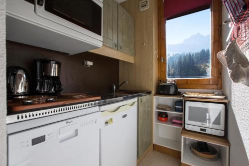 Elle comprend une petite cuisine avec des placards blancs et une fenêtre. dans l'établissement Quartier Crève Cœur - maeva Home - Appartement 2 pièces 4 personnes MAE-1221, à Valmorel