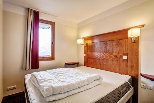 une chambre avec un grand lit avec une tête de lit en bois dans l'établissement Résidence La Marelle et Le Rami - maeva Home - Appartement 2 pièces 5 personnes Selection MAE-2243, à La Plagne Tarentaise