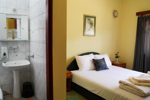 パリチにあるCountry House Majkin Salasのベッドのある寝室と洗面台のある浴室