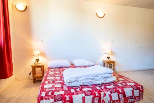 een slaapkamer met een bed met een rode en witte deken bij Le Chalet Le Grand Air - Studio pour 4 Personnes 193060 in Villarodin-Bourget